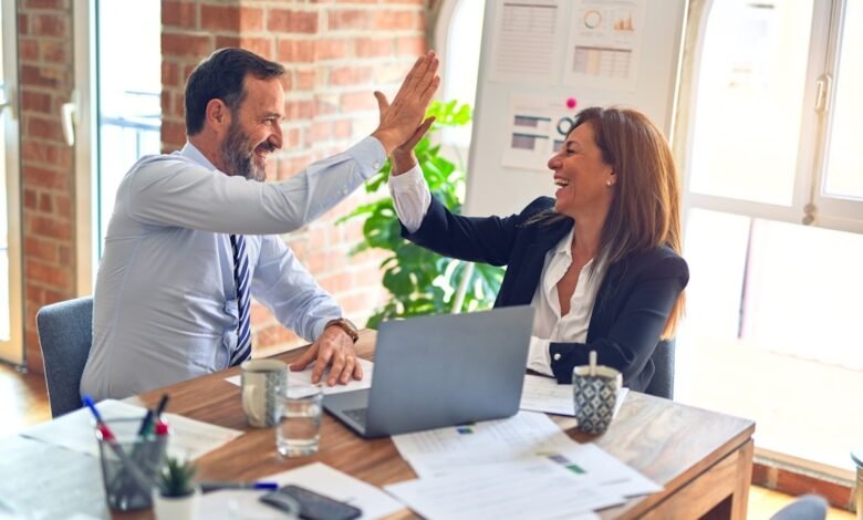 Two business people share a high five at a desk, symbolizing teamwork in the context of Panviva vs eGain.